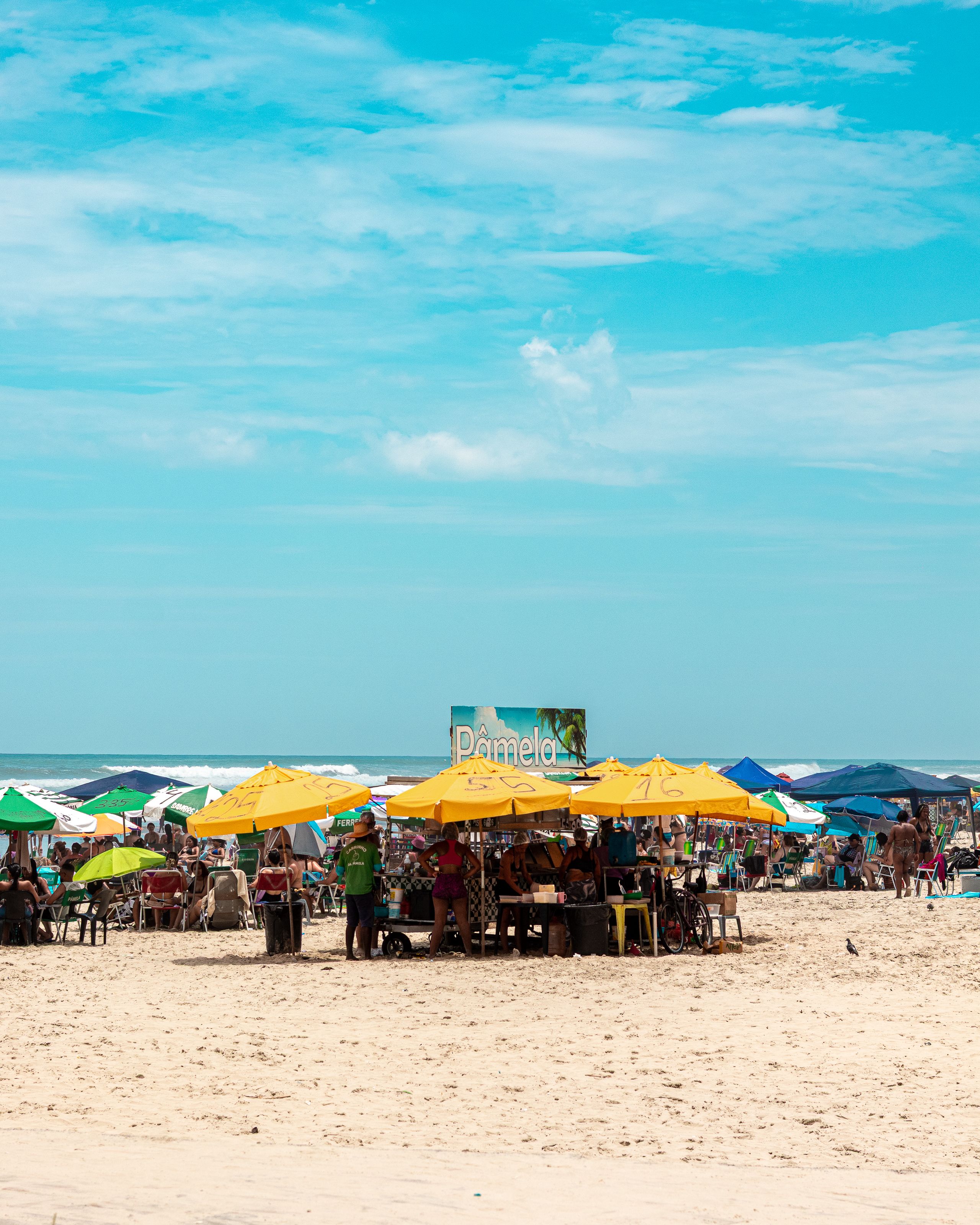 A lively beach scene with vibrant umbrellas and people enjoying a sunny day at the beach.