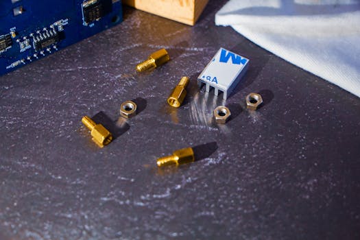 A detailed view of electronic parts including bolts and a heatsink on a metallic surface.