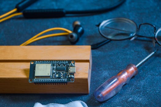 Close-up of an Arduino circuit board on a workshop table with tools and gadgets, showcasing DIY electronics.