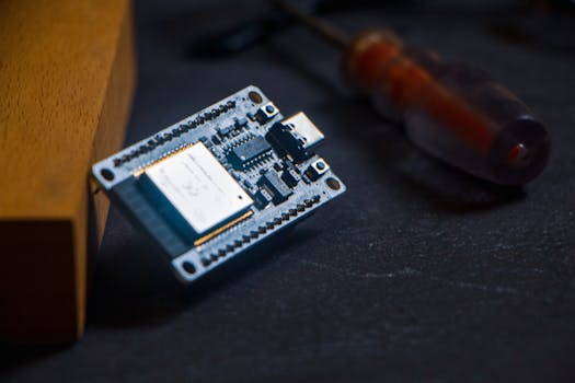 Microcontroller chip with screwdriver on dark surface, ideal for tech and innovation themes.