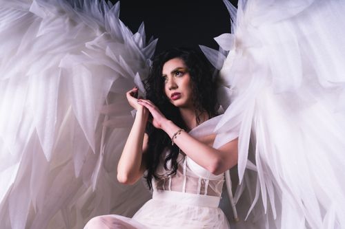 Free Captivating studio portrait of a woman with angelic wings, symbolizing grace and creativity. Stock Photo