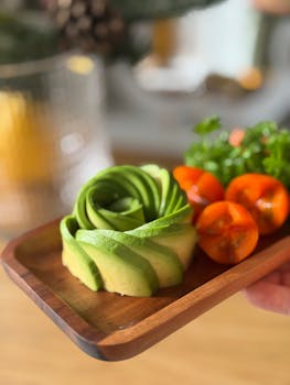 Elegant avocado rose with cherry tomatoes and parsley on a wooden platter.