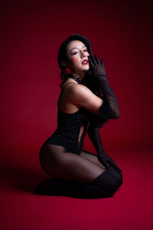 Free Stylish woman in black attire posing against a striking red backdrop. Stock Photo