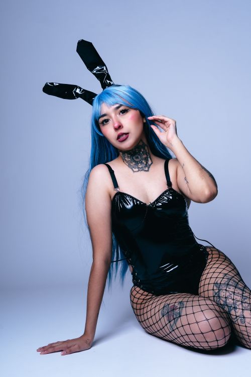 Free A striking portrait of a woman in anime cosplay featuring blue hair and black bunny ears. Stock Photo