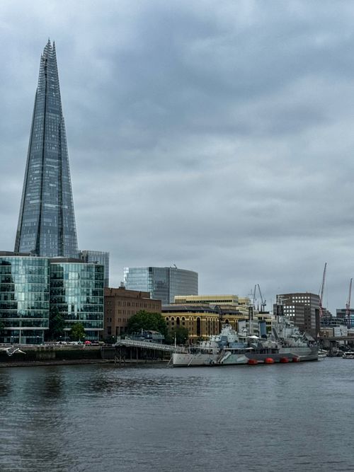 Free Dramatic view of London's Shard skyscraper beside River Thames under cloudy skies. Stock Photo