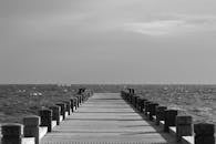 多云天空下，宁静的码头向海洋延伸的单色景象