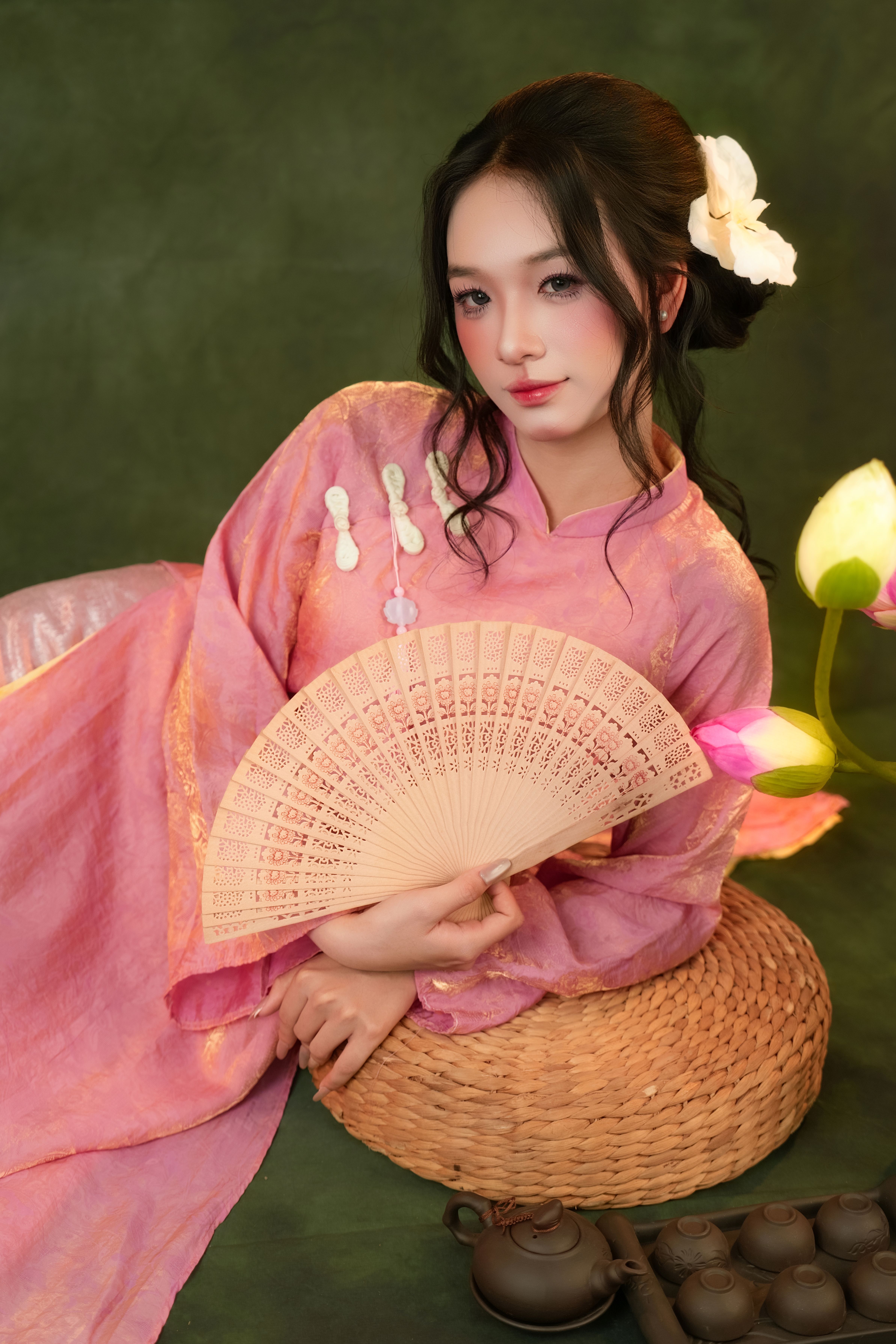 Charming woman in traditional attire holding a hand fan, expressing grace and culture.