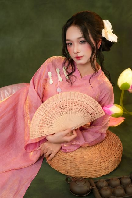 Charming woman in traditional attire holding a hand fan, expressing grace and culture.