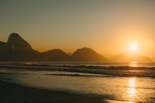 Breathtaking sunrise over a beach in Rio de Janeiro with iconic Sugarloaf Mountain.