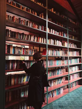A person browsing books in a warmly lit library with tall shelves, creating a serene atmosphere.