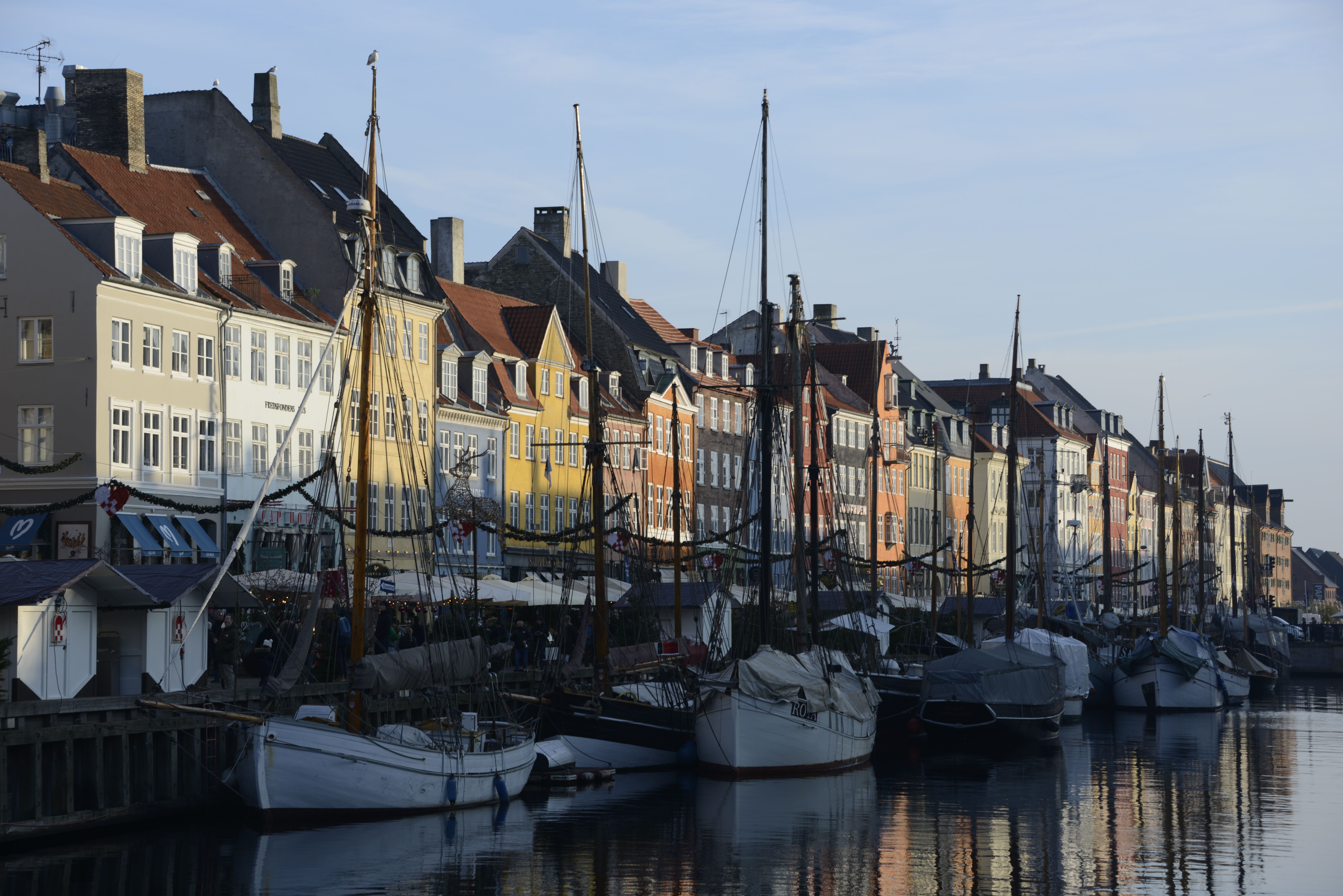 Scenic view of colorful buildings along Nyhavn Canal with boats, captured during the day in Copenhagen.