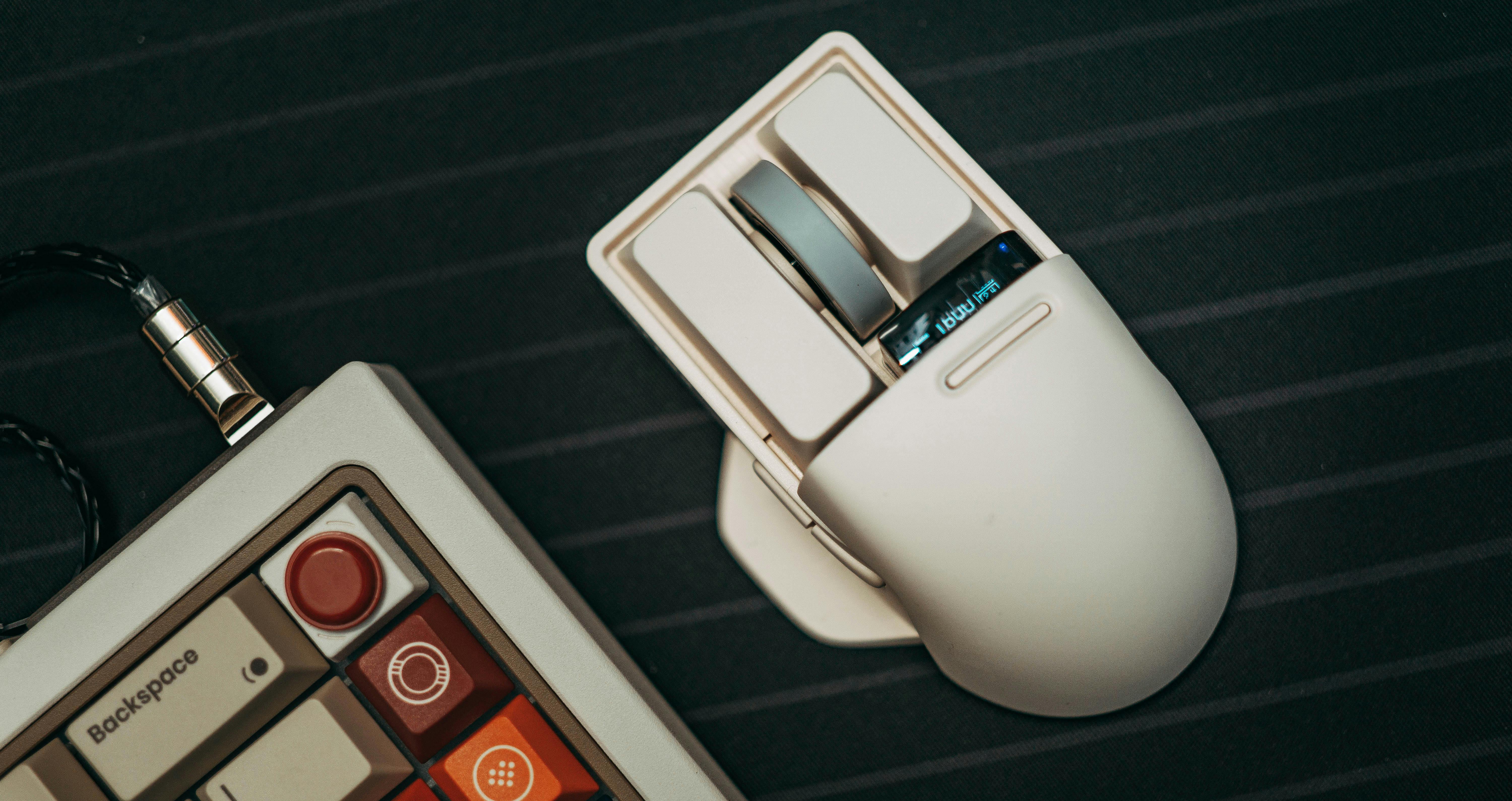 Kostenlos Eine elegante Computermaus und eine stilvolle Tastatur auf dunklem Untergrund. Moderne Technik-Basics für effiziente Arbeitsplätze. Stock-Foto