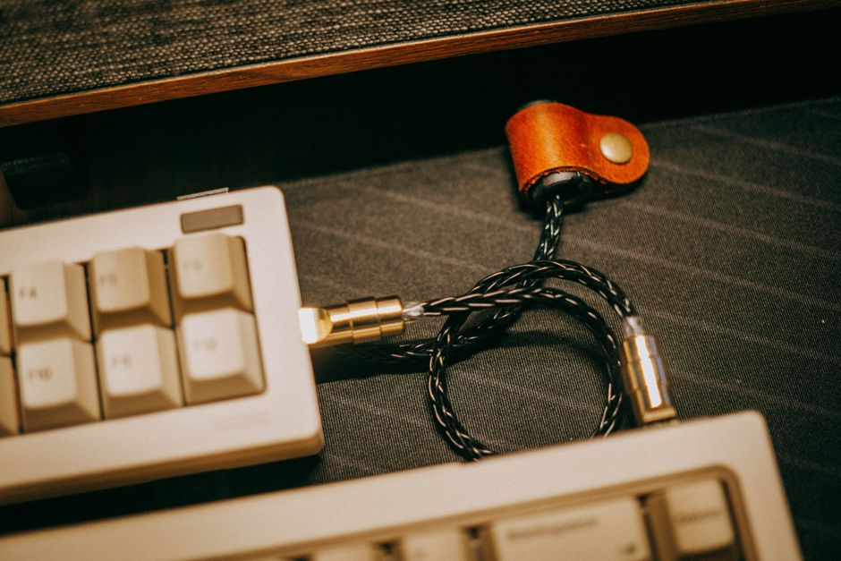 꼬임형 USB 케이블과 가죽 스트랩이 달린 빈티지 기계식 키보드의 클로즈업 사진.