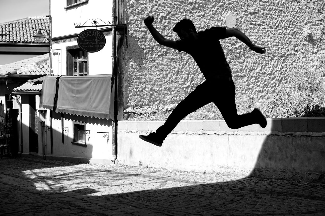 silhouette of a person leaping on a cobblestone street against an old