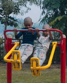 Two children playing on outdoor exercise equipment in a Lucknow park.