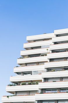 Elegant white terraced apartment building against a clear summer sky in La Grande-Motte, France.