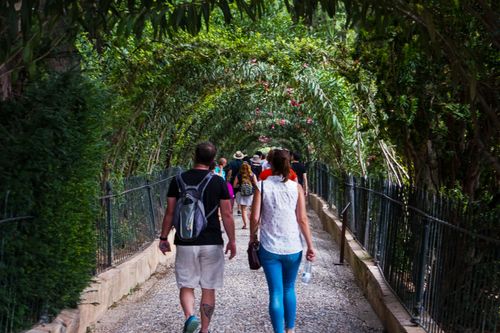 Free Tourists enjoy a walk through the lush, green arches in Granada, Andalusia, Spain. Stock Photo