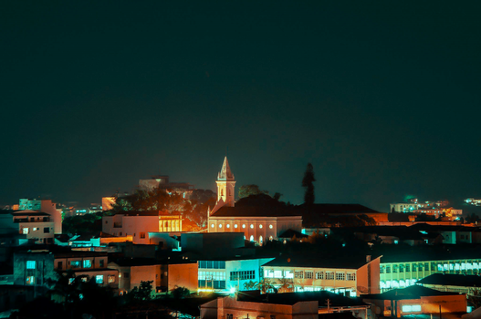 Beautiful cityscape at night showcasing illuminated buildings and a church tower.