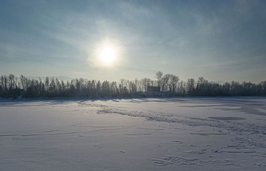 Scenic winter landscape featuring a frozen lake under the bright winter sun.