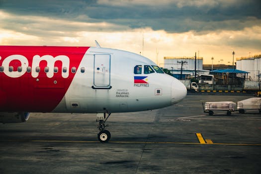 AirAsia airplane parked at a Philippine airport terminal during daytime with cloudy skies.
