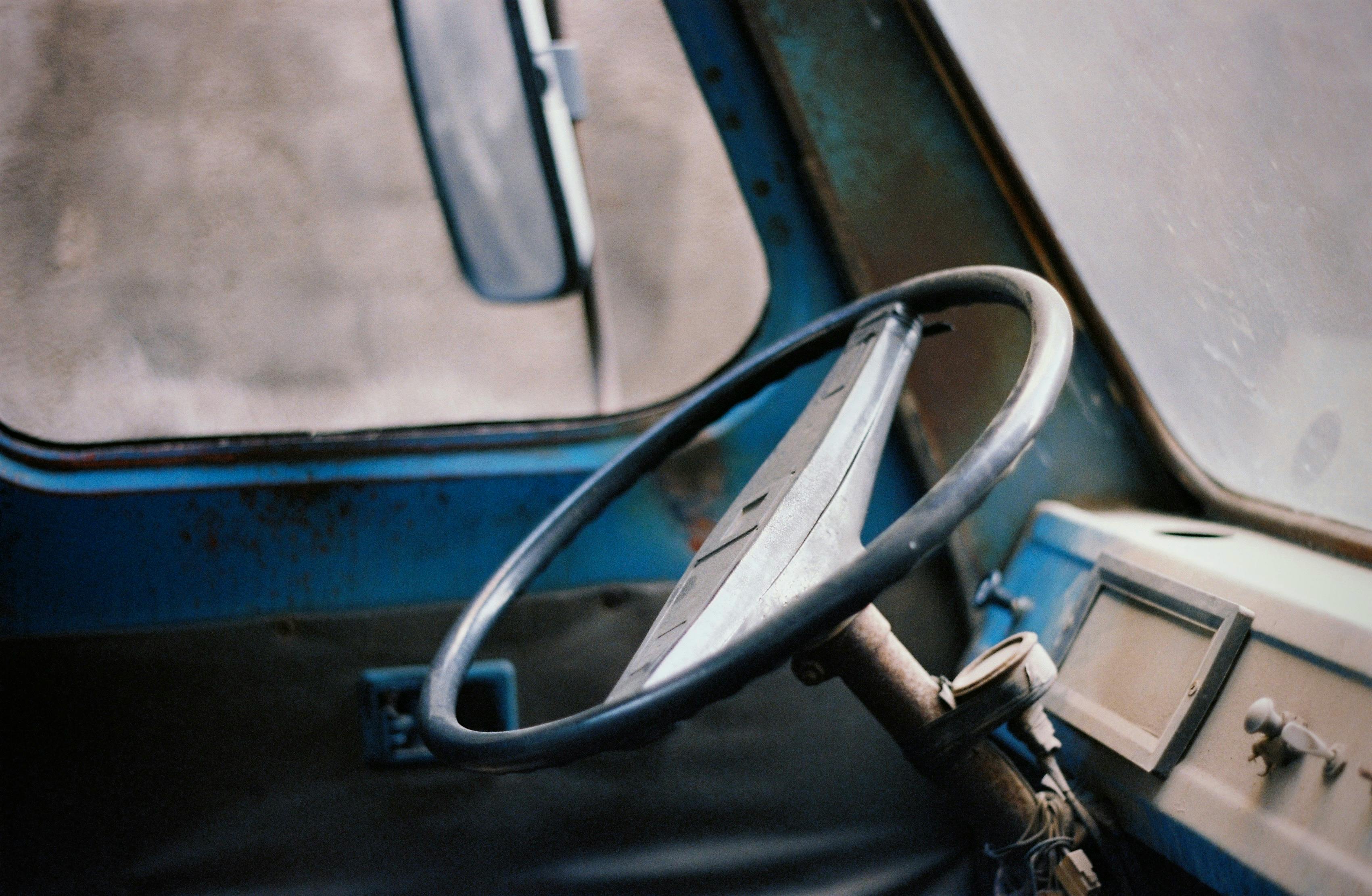 grátis Detalhe do interior de um carro antigo, com um volante azul enferrujado e texturas metálicas antigas. Foto profissional