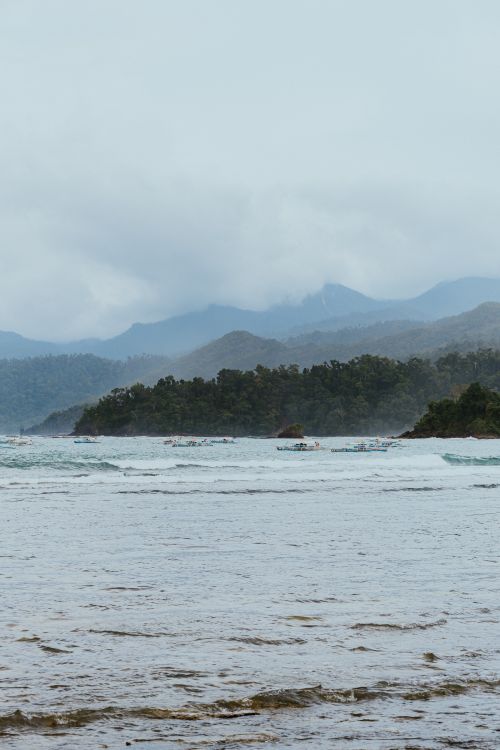 Free Breathtaking view of a tropical coastline with distant mountains and cloudy skies. Stock Photo