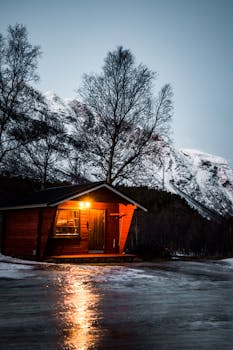 迷人的小屋坐落在挪威的冬季景观中，周围是白雪皑皑的山脉和冰冷的远景