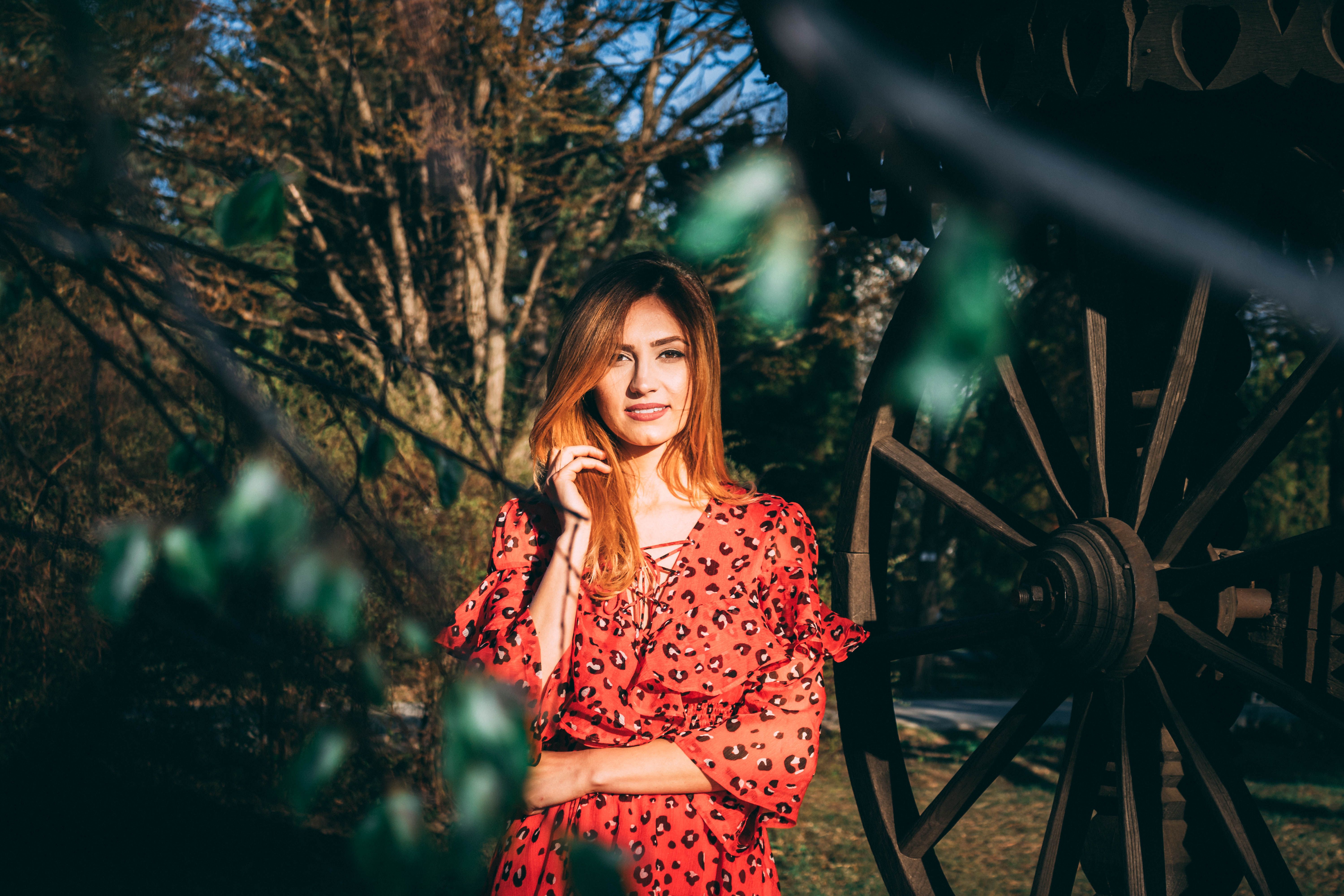 Woman in Red Dress Posing Outdoors by Wagon Wheel · Free Stock Photo