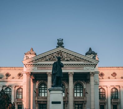 A classic building facade with a prominent statue captured in warm sunrise light, showcasing intricate architectural details.