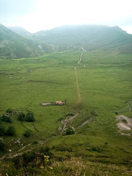 Aerial view of the lush green valleys and hills in Covadonga, Spain. Serene landscape with distant mountains.
