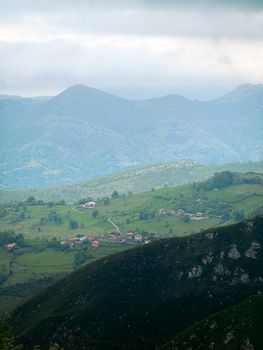 Picturesque landscape of Covadonga, Spain with lush green hills and distant mountains under a cloudy sky.