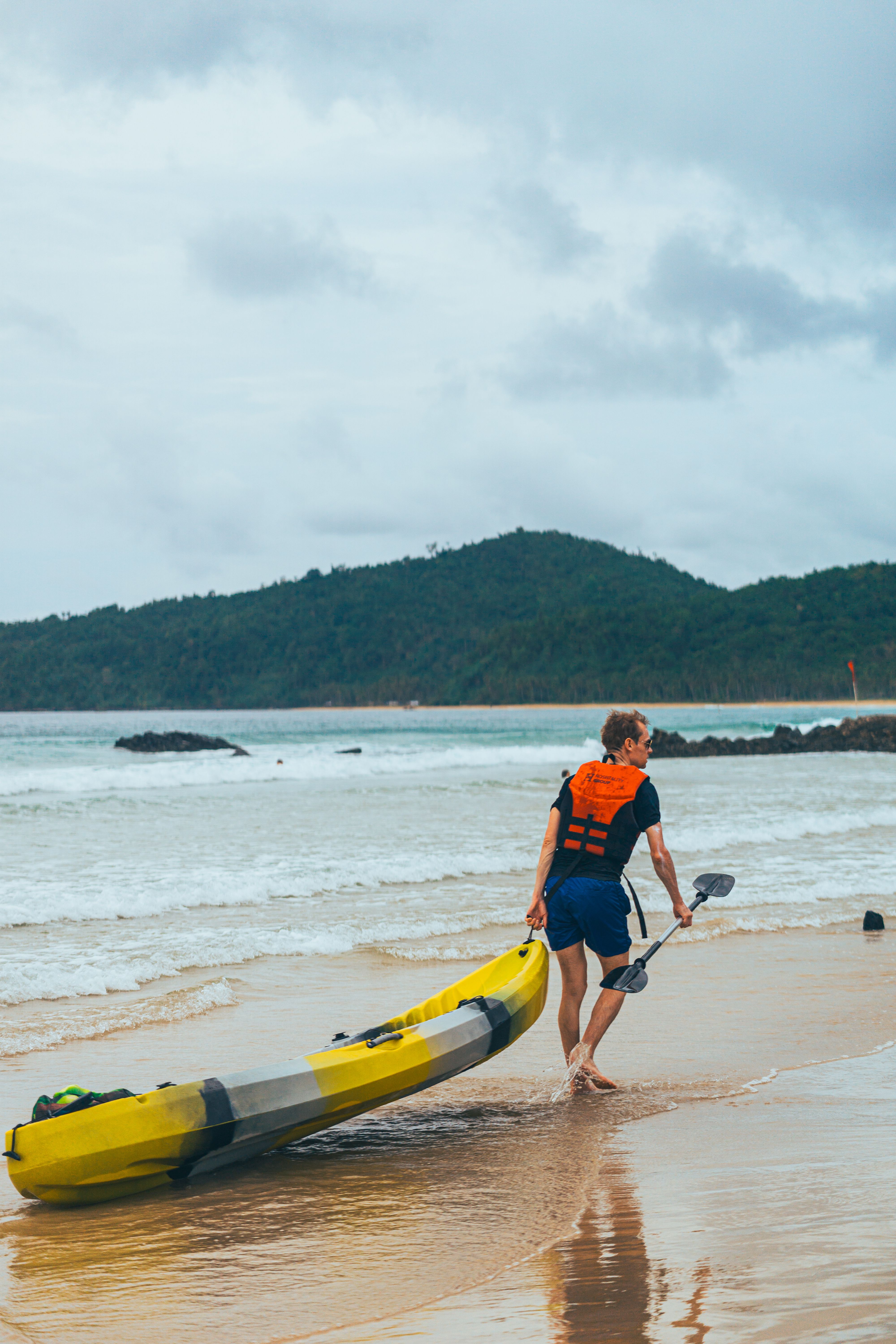 Paddler preparing a kayak on a tropical shoreline