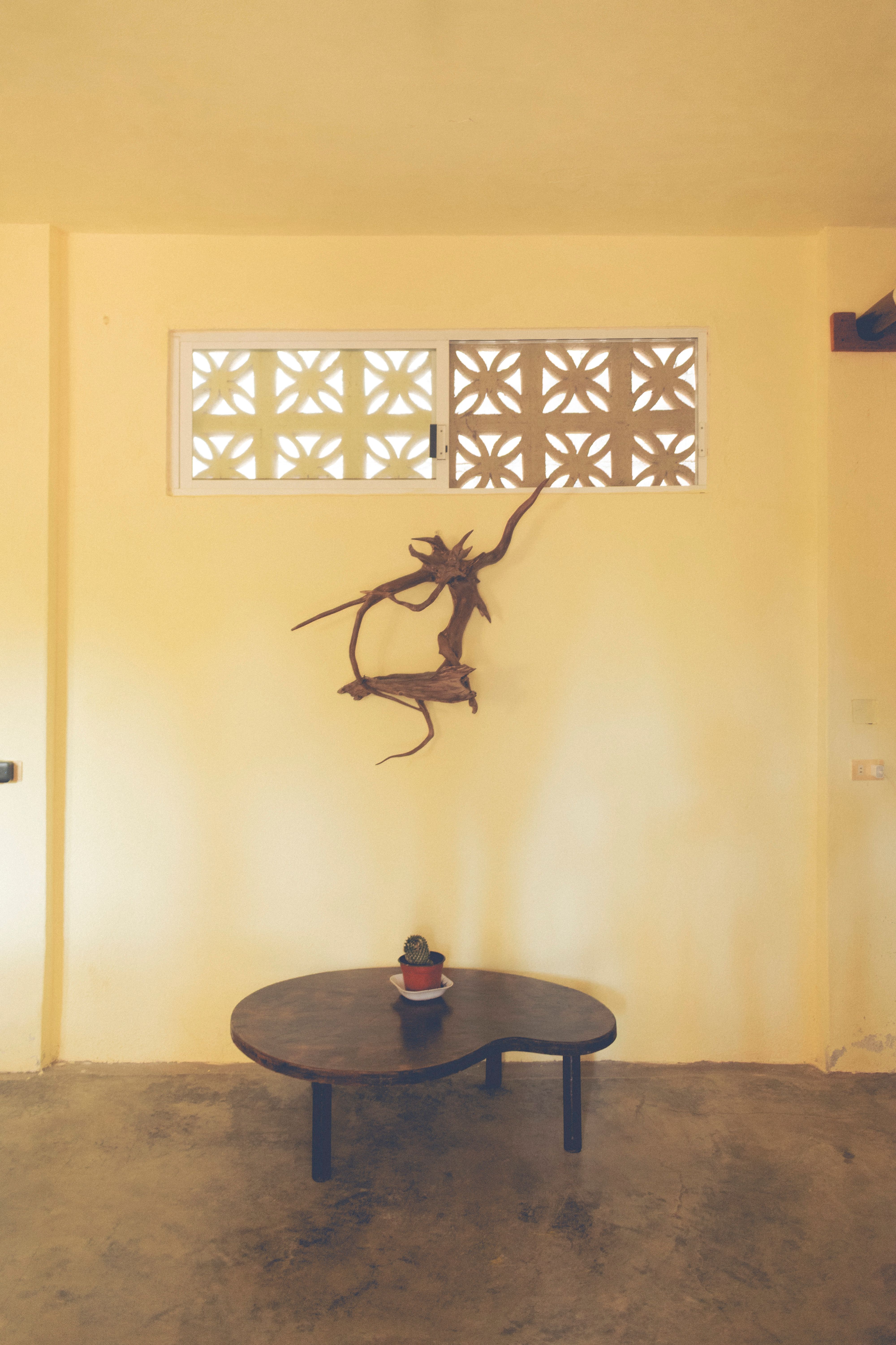 A stylish, minimalist indoor setting featuring a round table with a small plant and artistic wall decor.
