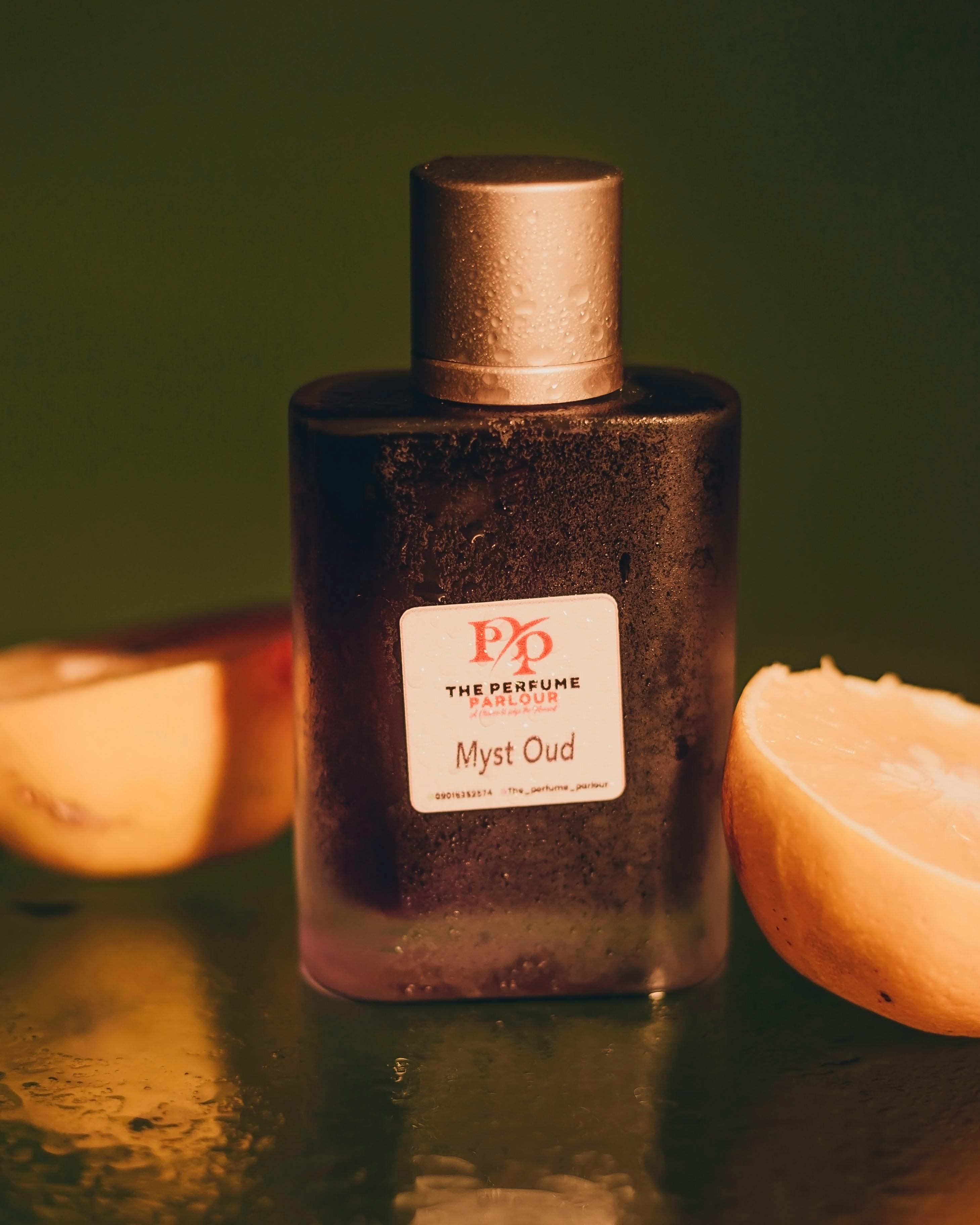 Elegant Myst Oud perfume bottle surrounded by fresh citrus for a luxurious aroma shot.