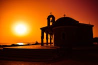 教堂的轮廓映衬着充满活力的日落天空，色调温暖，令人惊叹