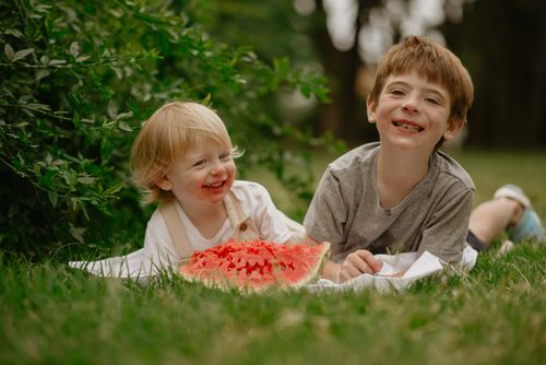 Free Two children smiling and enjoying watermelon on a summer day outdoors. Stock Photo