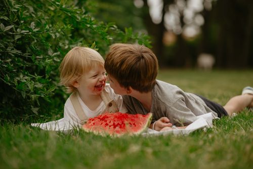 Free Two young children laughing and sharing a watermelon slice on a sunny summer day outdoors. Stock Photo