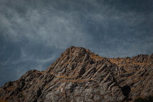 Free A rugged rocky mountain peak under a dramatic, cloudy sky conveying a sense of wilderness. Stock Photo