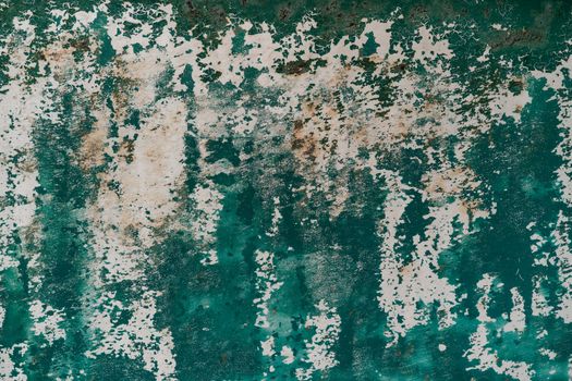 Close-up of a rustic, textured surface with peeling green and white paint.