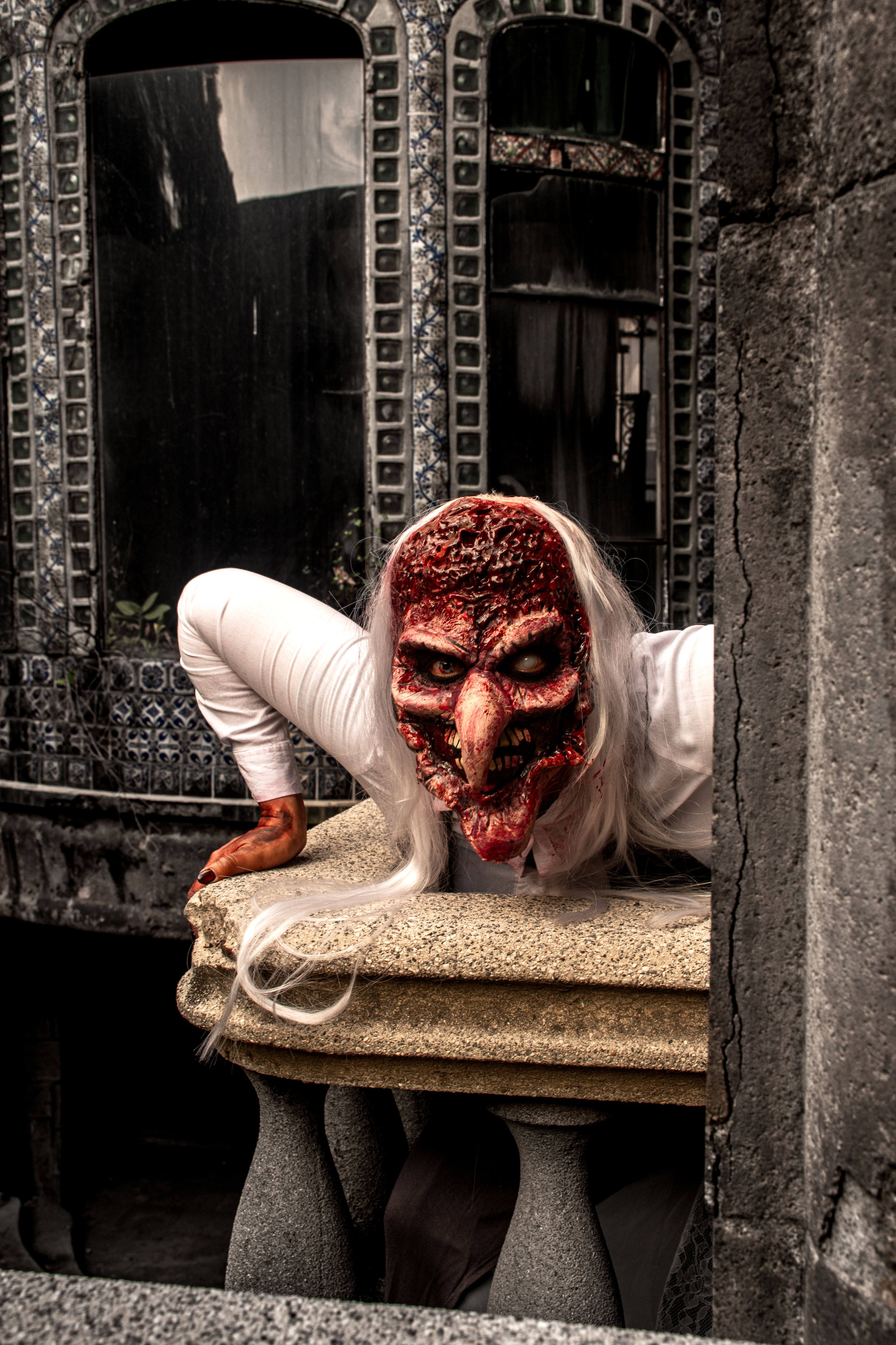 A creepy figure with a distorted mask peers out from a gothic architectural setting.