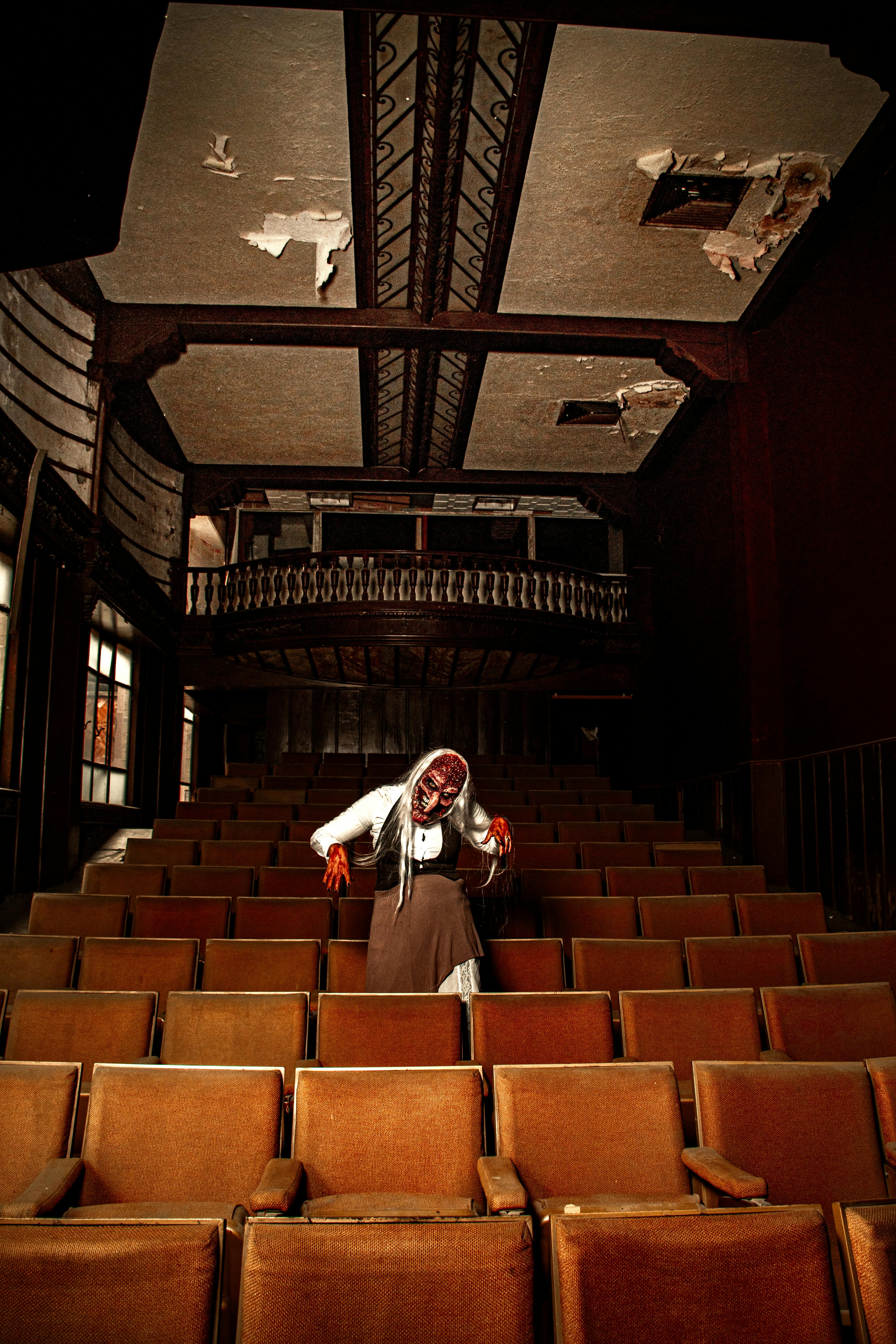 De franc Escena fosca i fantasmagòrica amb un pallasso esgarrifós en un teatre abandonat, sostre trencat. Foto d'estoc