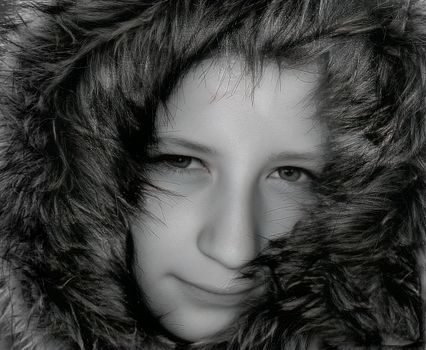 Black and white portrait of a child wearing a fur hood, expressing warmth and coziness.