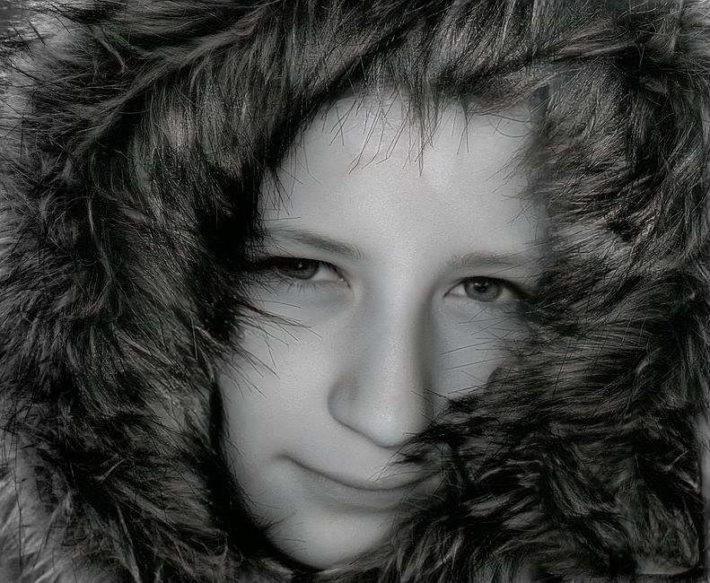 Black and white portrait of a child wearing a fur hood, expressing warmth and coziness.
