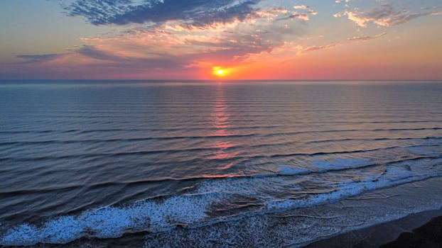 Stunning aerial view of a serene sunrise over the ocean at Costa Azul, Argentina, capturing tranquil waves and vibrant skies.