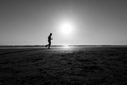 Free Black and white photo of a man jogging on Costa Azul beach at sunset, Buenos Aires. Stock Photo