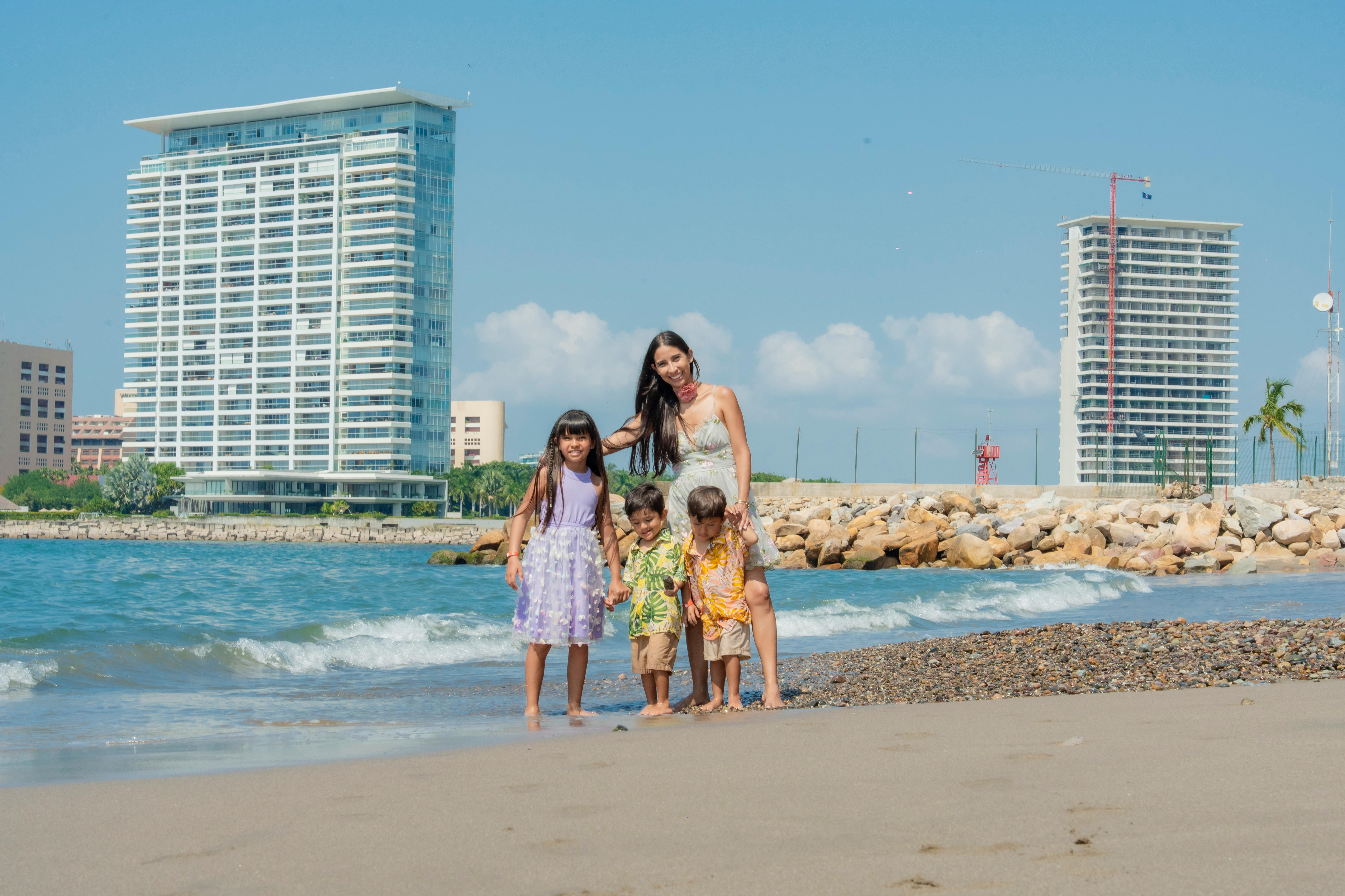 A family having fun on a sunny beach day with skyscrapers in the background. - Photo by Luis Becerra  Fotógrafo on Pexels