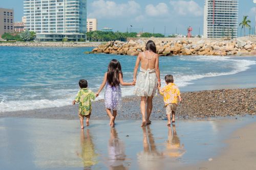 Free A family enjoys a sunny beach day with children playing in the sand and waves. Stock Photo