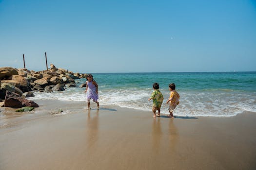 Children enjoying a sunny day playing at the beach with waves and sand.