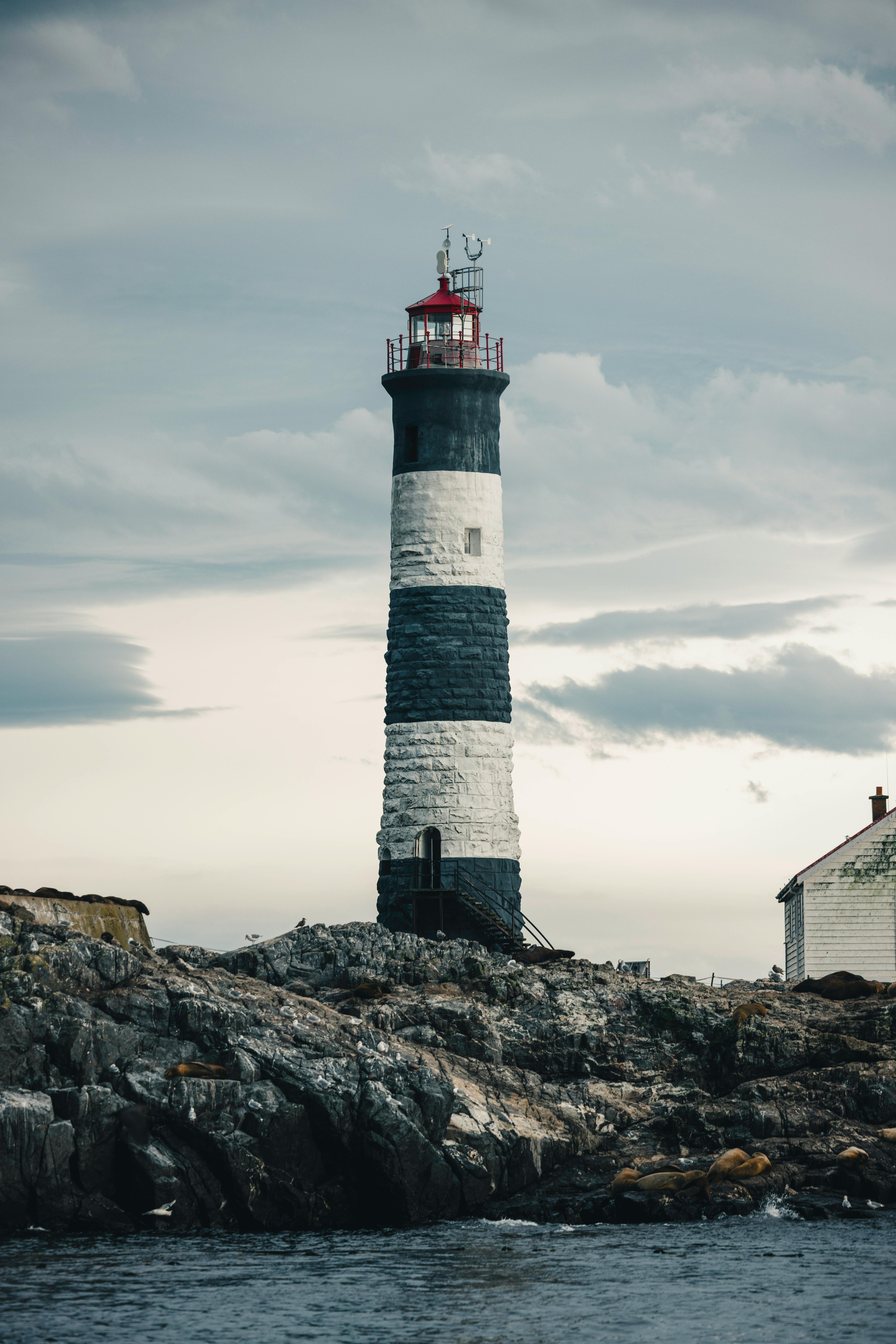 Dramatic view of a lighthouse on a rocky coast under a moody sky, perfect for travel and navigation themes.