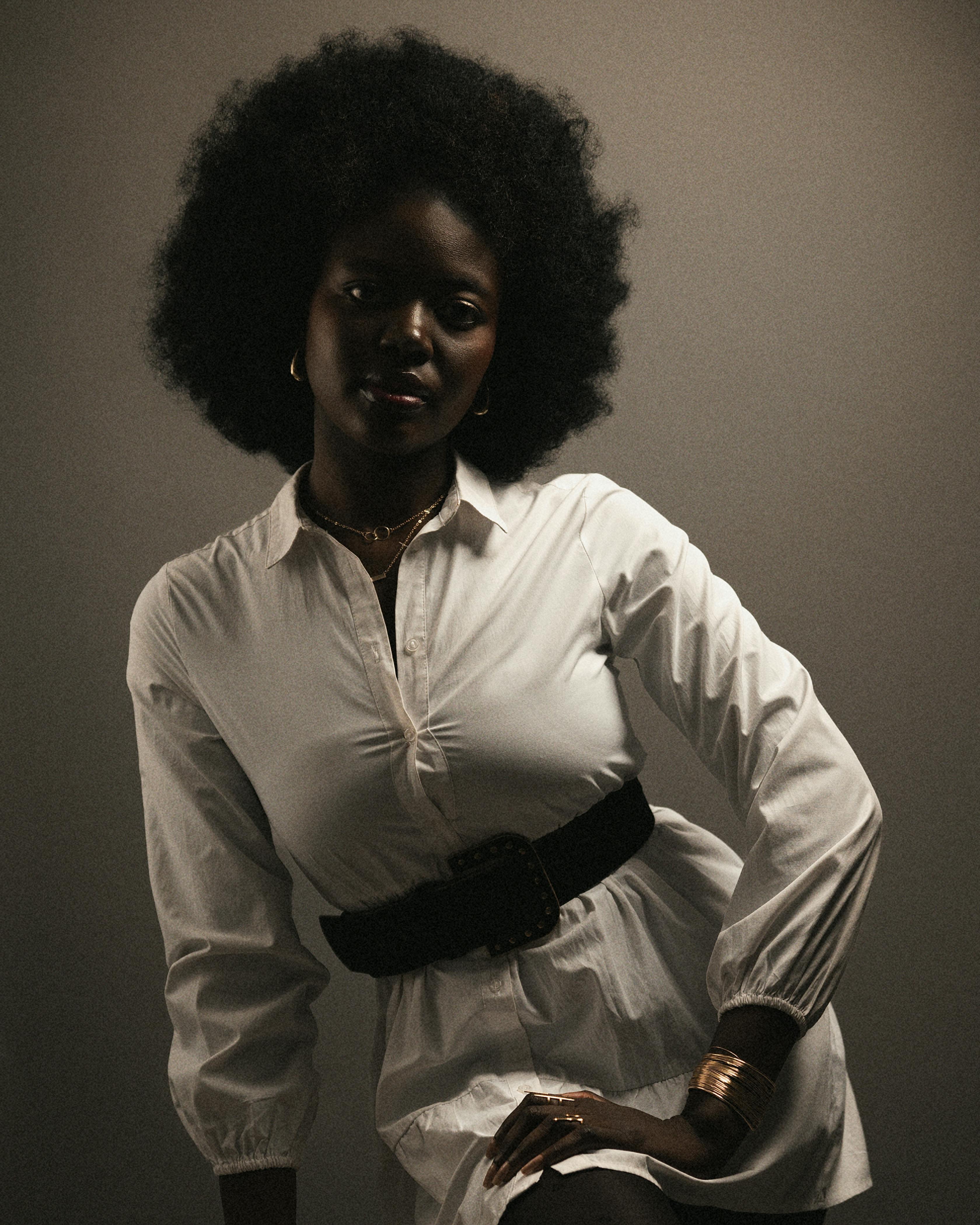 Gratis Stilig portrett av en kvinne i hvit kjole som viser frem naturlig afrohår. Arkivbilde